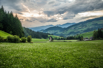 Fototapeta premium Dolomites, Italy - July, 2019: Green alpine valley with view of Santa Maddalena village church, Val di Funes, Dolomiti Mountains, Italy