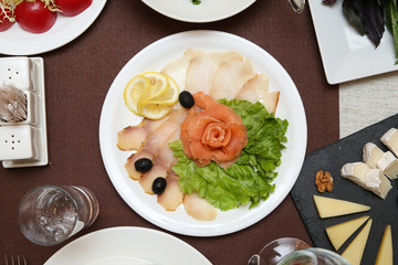 fish food sliced on a round white plate. background of the served table top view