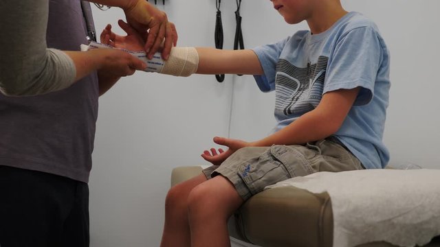 Child at the doctors office getting a his arm wrapped.