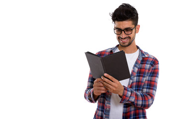 Portrait of young bearded Persian hipster man reading book