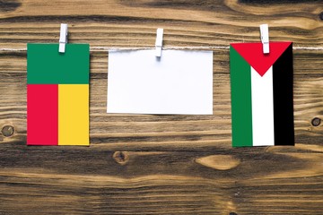 Hanging flags of Benin and Palestine attached to rope with clothes pins with copy space on white...