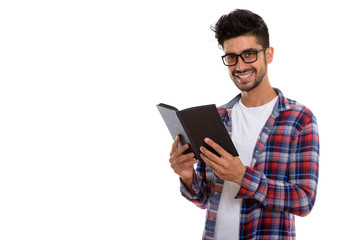Portrait of young bearded Persian hipster man reading book