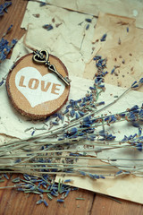 Bouquet of dried lavender flowers,  heart decor, vintage key and old paper on rustic wooden background. romantic nostalgic composition. close up. soft selective focus.
