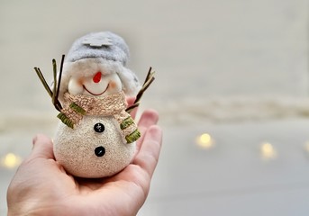 Single white cheerful snowman smiling and standing on hand with snow and lights background