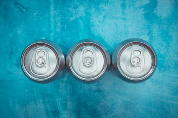 Silver metal energy drinks metal cans on blue color texture background top view