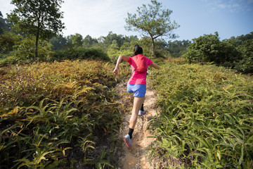 Woman trail runner running up on mountain slope in tropical forest