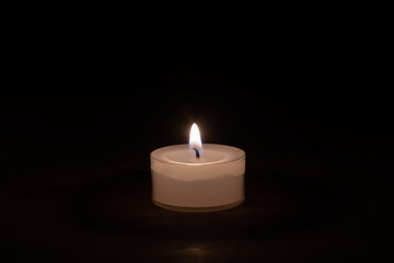 Fototapeta na wymiar Closeup of a candle on a wooden table with dark background - middle
