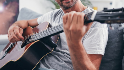 Man playing acoustic guitar in the living room.