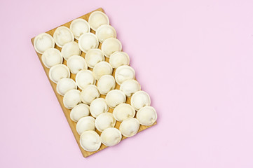 Tasty Homemade Frozen Pelmeni on Wooden Board on Pink Background Russian Dish Background With Frozen Russian Ravioli or Pelmeni Horizontal Top View