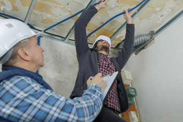 builders putting or repairing up a suspended ceiling
