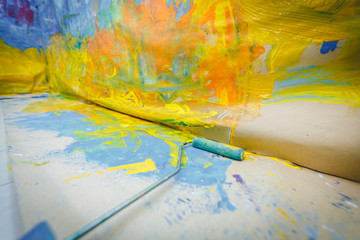 Obraz premium wide angle photo of watercolor painted wall in drawing room lesson classes in school or kindergarten or education centre. Drawing atmosphere. blue and yellow color. paint roller lies against the wall