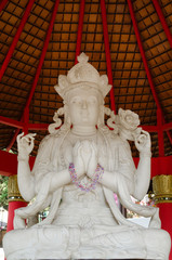 Stunning white marble four armed buddha in deep meditation under a pillared pagoda shelter