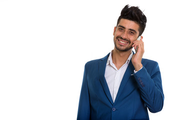 Young handsome bearded Persian businessman in suit using phone