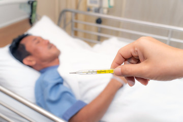 Fever, Close-up medical thermometer,An Asian man is sleeping on a medical bed in hospital ward 