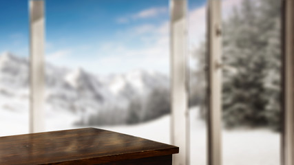 Table corner with space for your product. Blurry winter window with the door open. Beautiful landscape of snowy mountains and festive fir with snow covered branches. Place for your products or inscrip