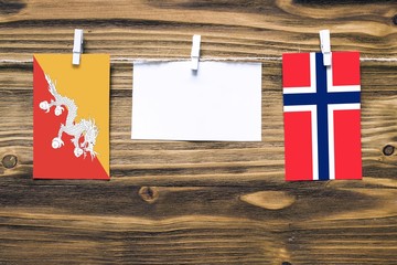Hanging flags of Bhutan and Bouvet Islands attached to rope with clothes pins with copy space on...