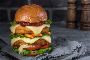 Hamburger with a double serving of meat, tomatoes, salad, onions on a wooden board in a restaurant.Copy space