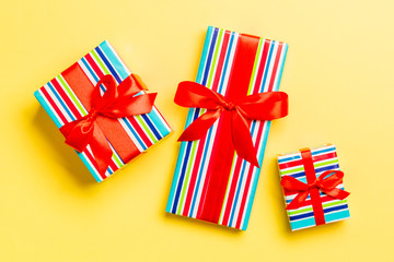 wrapped Christmas or other holiday handmade present in paper with red ribbon on yellow background....