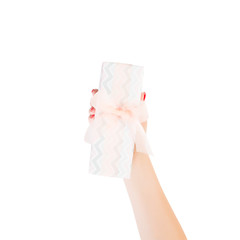 Woman hands give wrapped Christmas or other holiday handmade present in colored paper with orange ribbon. Isolated on white background, top view. thanksgiving Gift box concept