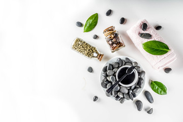 Flat lay composition with spa stones, green leaves and cosmetics, top view copy space