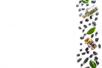 Flat lay composition with spa stones, green leaves and cosmetics, top view copy space