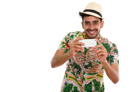 Young handsome bearded Persian tourist man using phone
