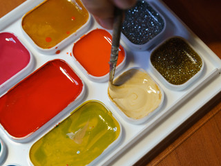 Photography of various colorful and bright paints for drawing and paintbrush. Concepts of education and development of creativity. Red, blue, green, yellow, pink colors.