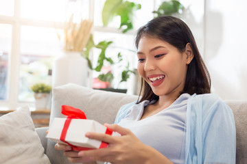 Young happy Asian pregnant woman holding gift box with smiley face.