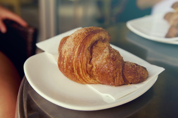 Sweet croissant served on a plate in a bar, typical italian breakfast with coffee