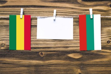 Hanging flags of Bolivia and Bulgaria attached to rope with clothes pins with copy space on white note paper on wooden background.Diplomatic relations between countries.