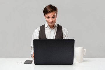 Businessman in a white t-shirt and grey vest is shocked checking infor