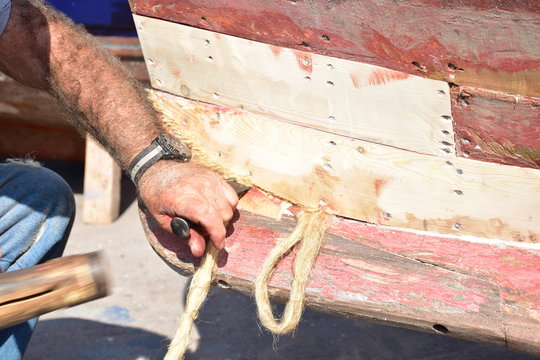  Calafataggio,  tecnica di impermeabilizzazione dello scafo in legno, eseguita dal mastro calafato. Lavoro eseguito su una barca tradizionale in legno. Sicilia, Palermo- localit&agrave; Sferracavallo