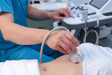 Ultrasound diagnostic of stomach on abdominal to woman in clinic, closeup. Doctor runs ultrasound...