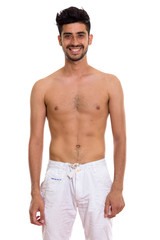 Fototapeta premium Studio shot of young happy Persian man smiling while standing sh