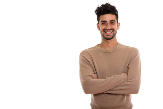 Studio shot of young happy Persian man smiling with arms crossed