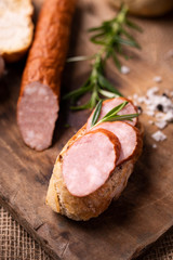 Sandwich with a smoked, pork sausage cut in slices in a rustic style composition.
