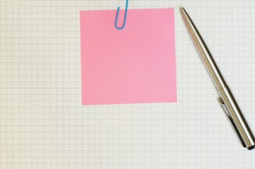 A pen and sticky note paper on blank grid paper