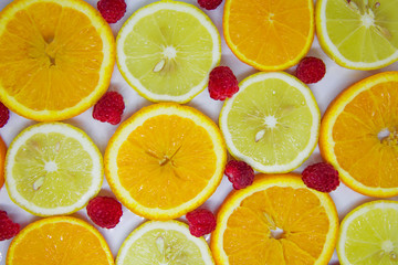 slices of orange and lemon and raspberries on white. Looks like a background