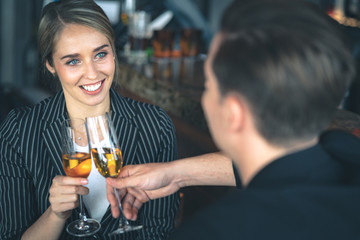 Couple clinking glass of champagne at the bar and smiling.