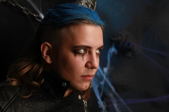 Teen Alt Boy With Blue Hair And Shaved Head Dressed In Black On Dark Background