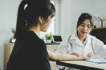 Asian doctor measuring patient pulse for checking measure pulse in annual health check,Medical student on treatment in desk prescription clipboard consultation with gown stethoscope in clinic hospital