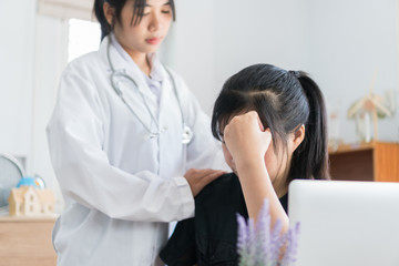 Fototapeta na wymiar Young patient serious headache siiting on table, Asian female doctor talking for comforting for peace of mind, Medicine student treatment in hospital concept