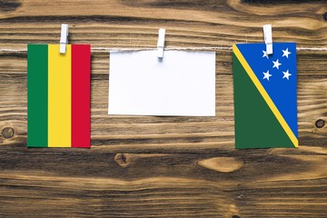 Hanging flags of Bolivia and Solomon Islands attached to rope with clothes pins with copy space on...