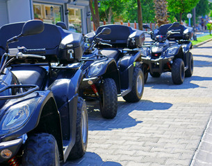 Black ATVs parked on the street of a southern resort town