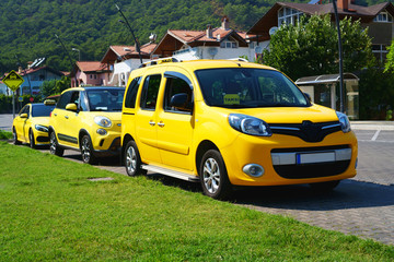 Yellow taxis in a resort town on a street near a green lawn.