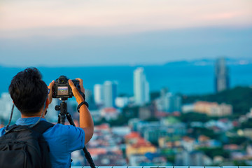 Obraz premium Senior male tourist using professtional camera (Dslr) taking a photo of Pattaya view. Chonburi, Thailand.