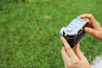 Closeup of camera model carried by woman trainee's hand with garden background. 