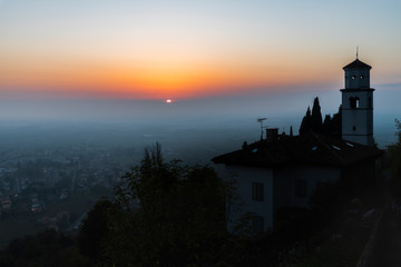 Fototapeta na wymiar Sunset from the Cormons hill. Among fog, vineyards and fiery colors. Italy