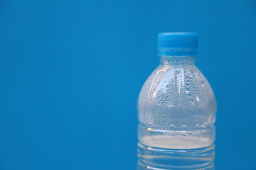 Fototapeta premium Closeup of a bottle of drinking water with blue background.