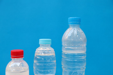 Closeup of three bottles of drinking water with blue background